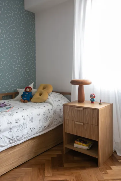 Habitación infantil con cama de madera, papel tapiz azul con patrón y mueble de arrimo — proyecto Lacroze, por Estudio Losa, en Belgrano